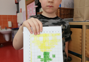chłopie prezentuje wykonane dyktando graficzne - wiosenny kwiat